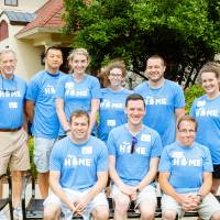Alumni pose in front of the Alumni House